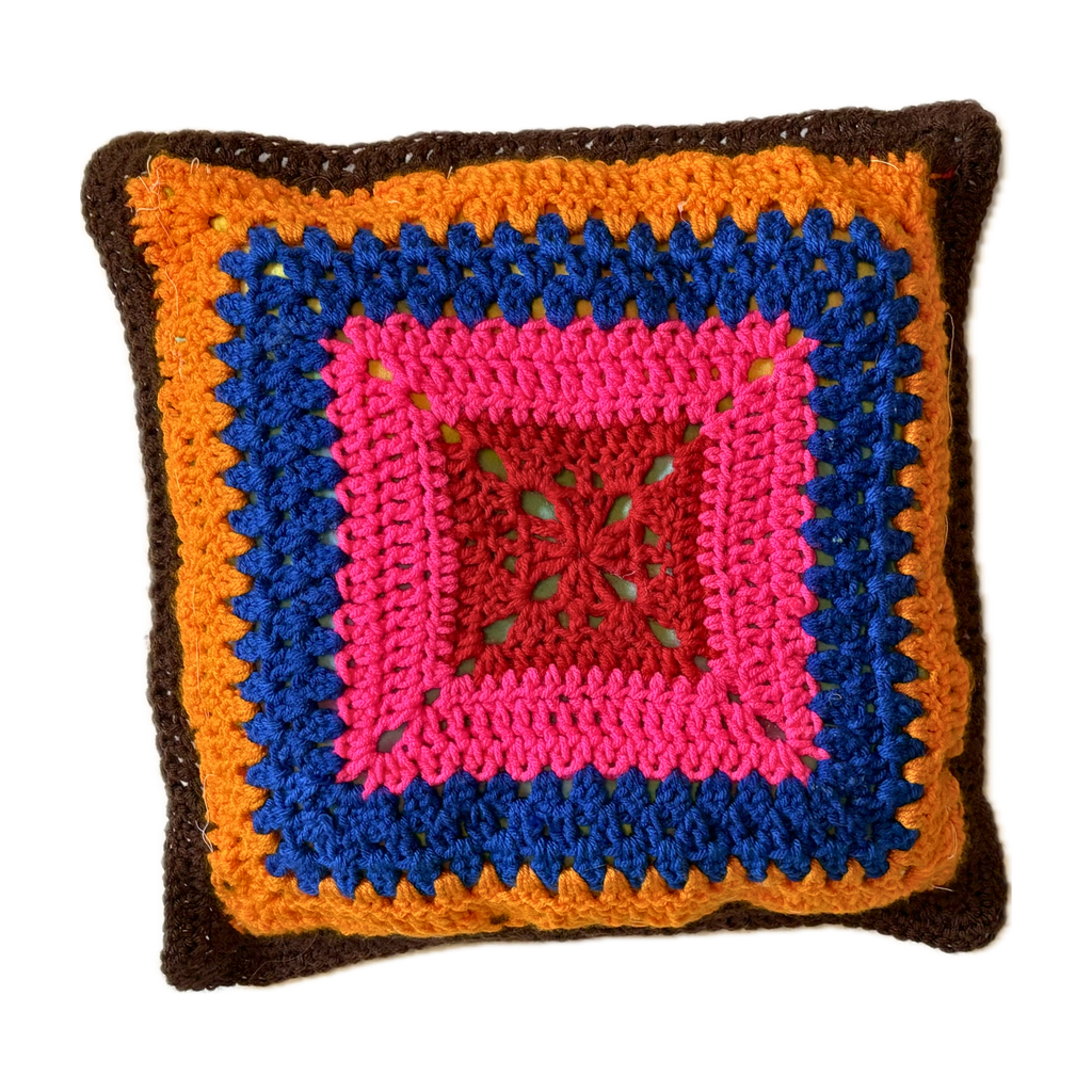 Colorful crocheted pillow with a square design on a white background