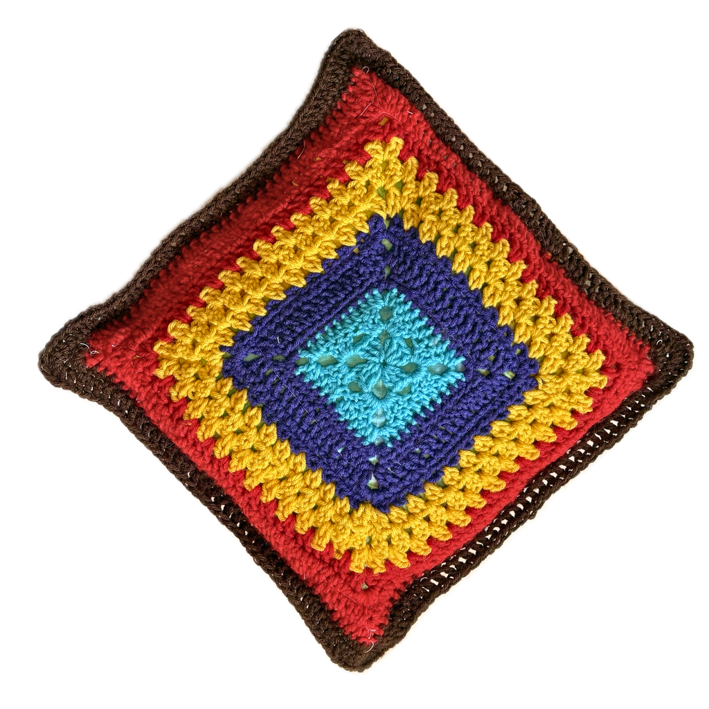 Colorful crocheted square pillow with a diamond pattern on a white background