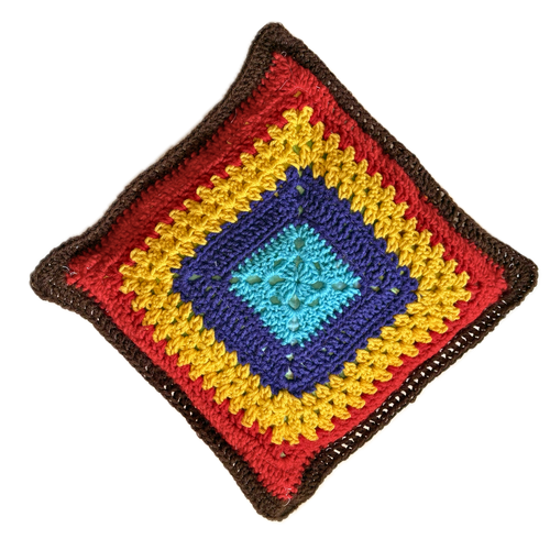 Colorful crocheted square pillow with a diamond pattern on a white background