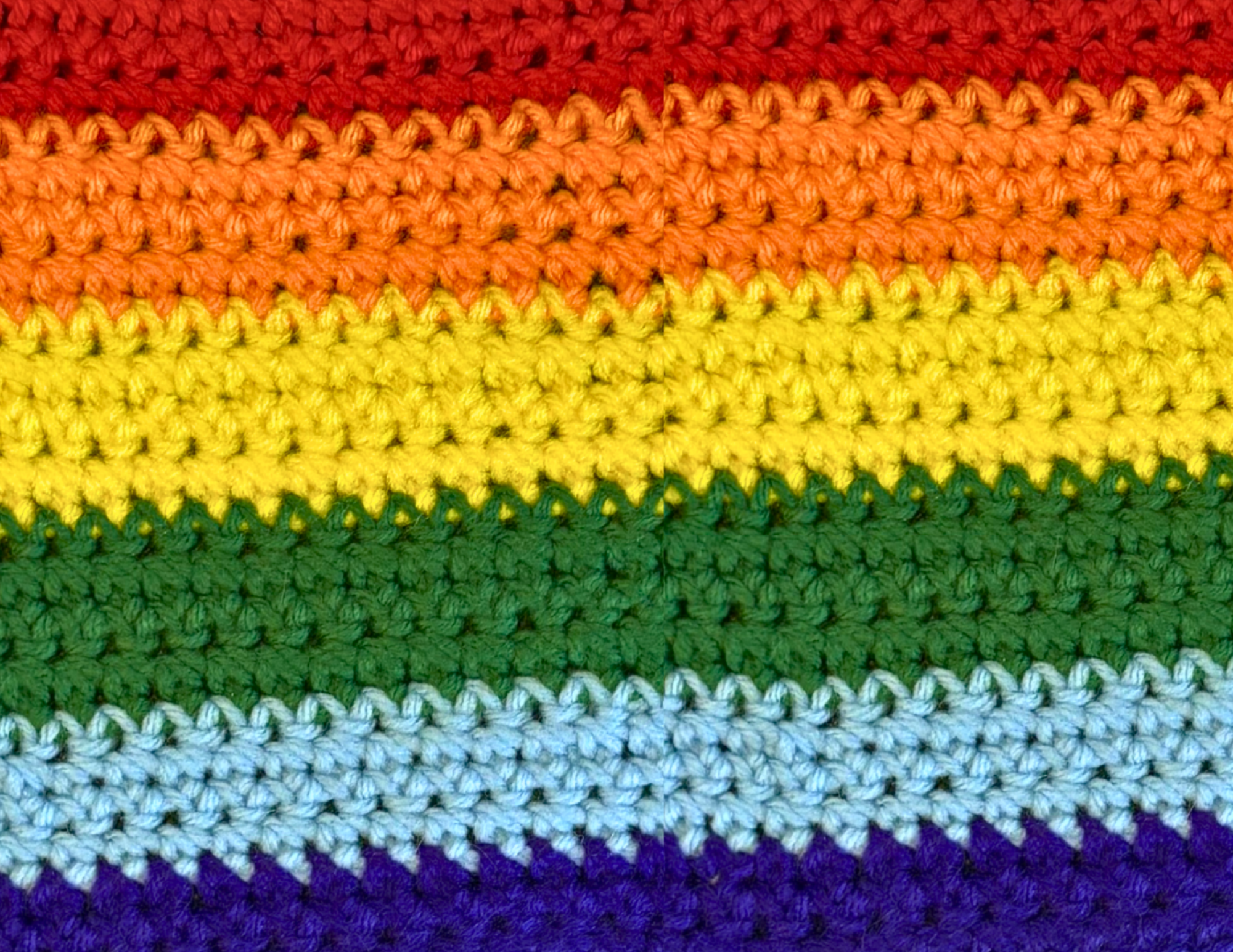 Close-up of a crocheted fabric with rainbow stripes.