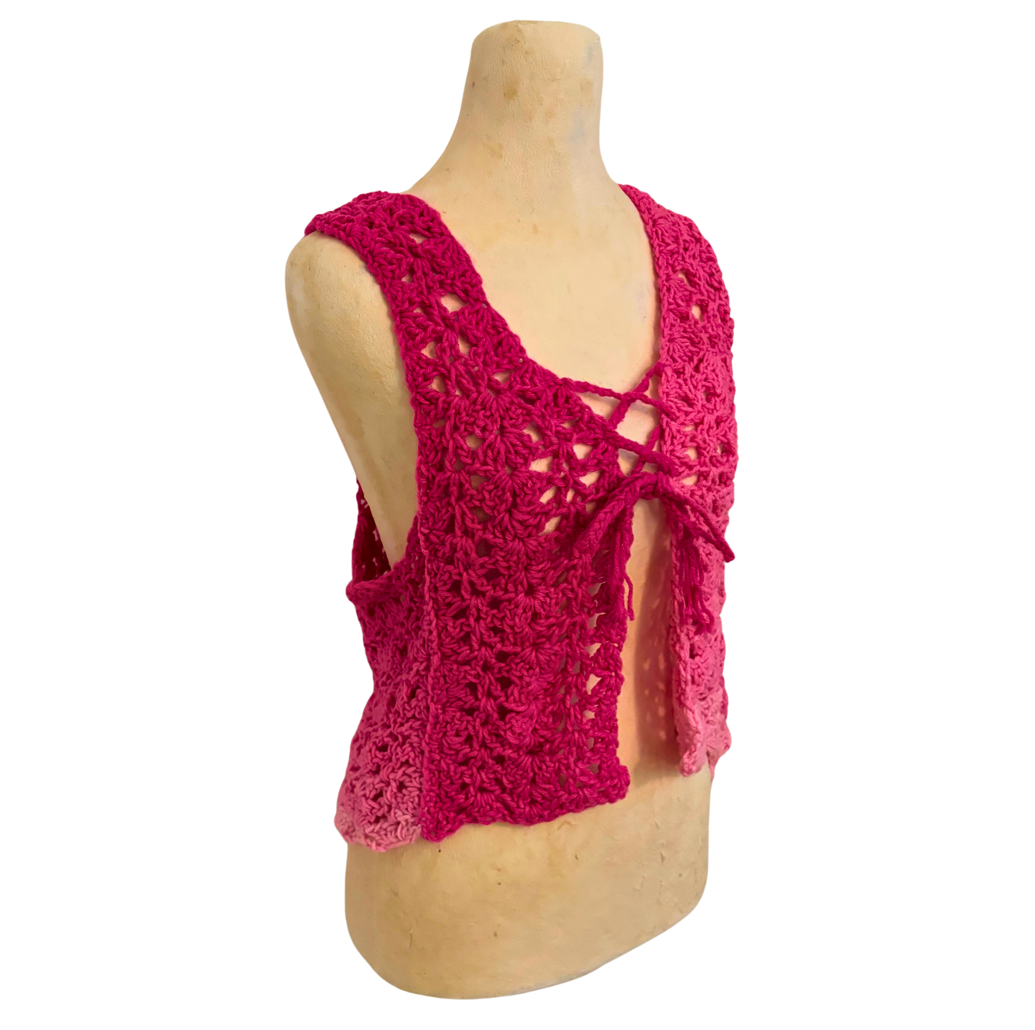 Pink crochet top on a mannequin against a white background