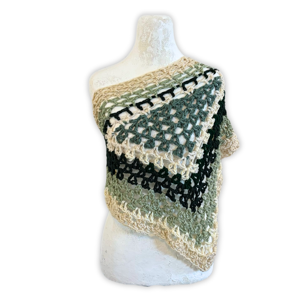 Crocheted shawl with green, black, and beige pattern on a mannequin against a white background