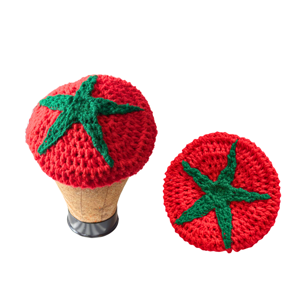 Two crocheted tomato-shaped hats with green stems on a white background